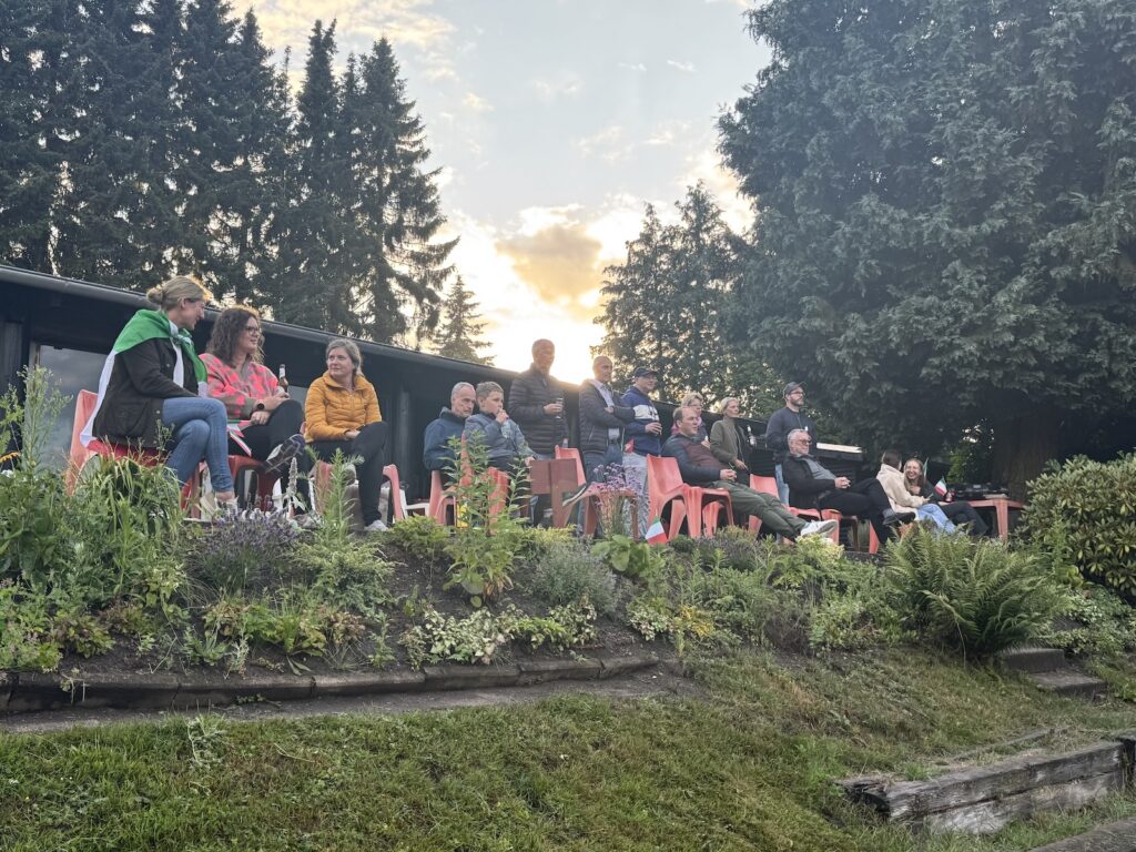 Menschen im Grünen schauen auf einen Tennisplatz