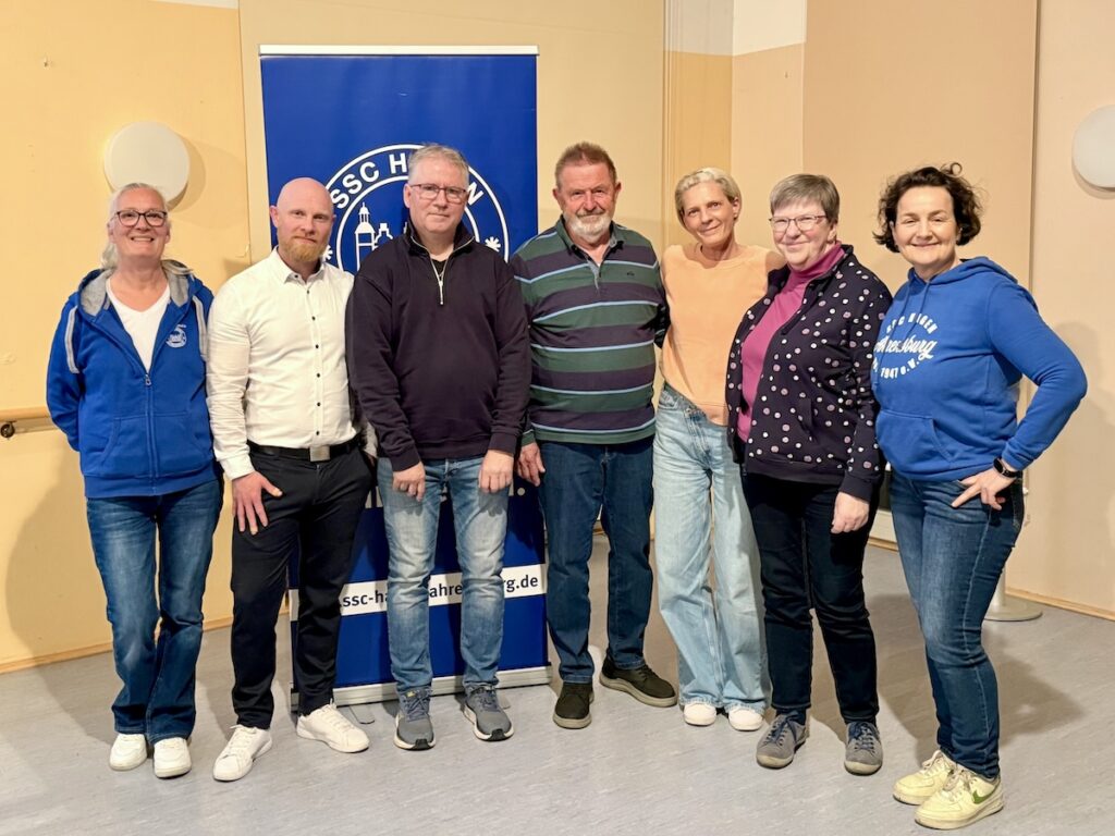 7 Personen stehen nebeneinander vor dem Logo des SSC Hagen Ahrensburg