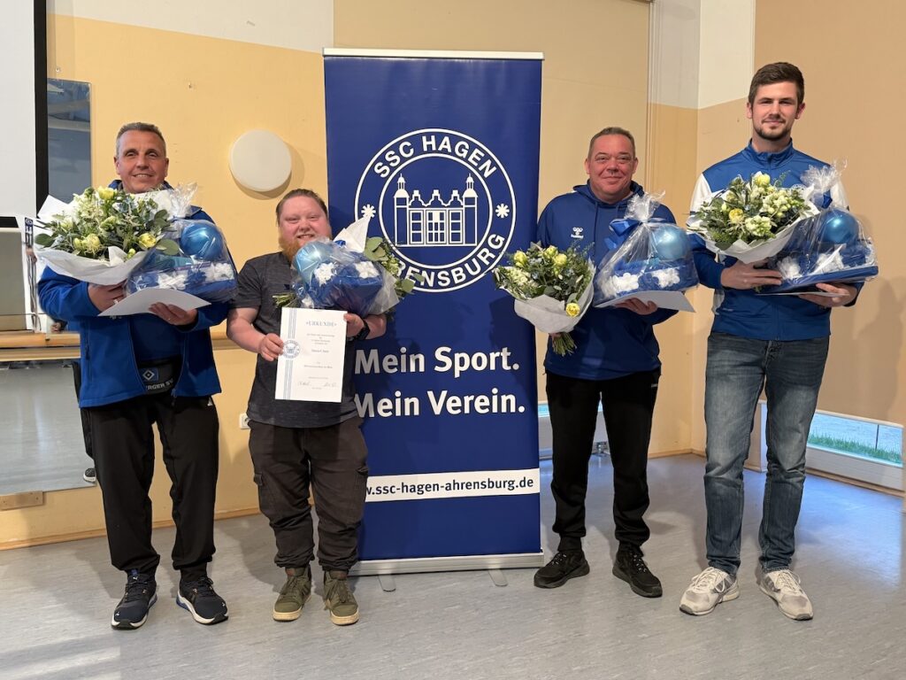 4 Männer mit Geschenkkörben und Blumensträußen vor einem Banner des SSC Hagen Ahrensburg