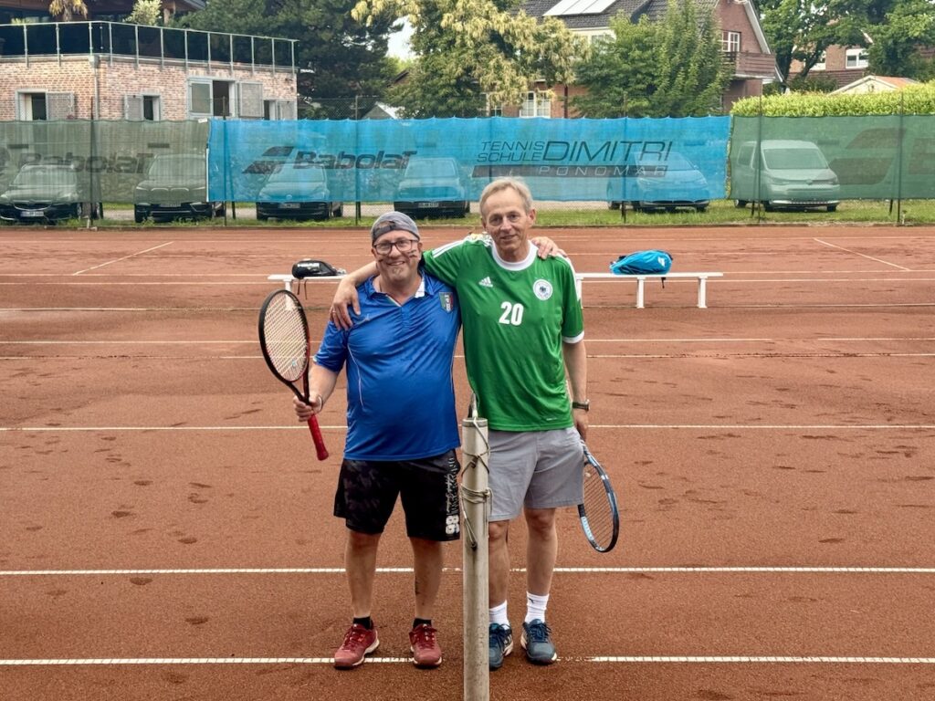 Zwei Männer auf einem Tennisplatz, Arm in Arm am Netz